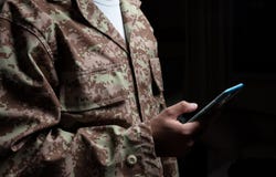 Ung soldat som rymmer ett mobiltelefonanseende på svart bakgrund arkivfoto Ung soldat som rymmer ett mobiltelefonanseende på svart bakgrund arkivfoto