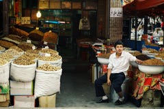 ung uyghurpojke på marknaden som säljer muttrar och kryddor och torkade frukter arkivfoto ung uyghurpojke på marknaden som säljer muttrar och kryddor och torkade frukter arkivfoto