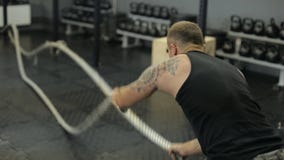 Ung vuxen man som gör crossfitgenomkörare med ledde rep lager videofilmer Ung vuxen man som gör crossfitgenomkörare med ledde rep lager videofilmer
