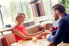 Unga par på datum i den sittande mannen för restaurang som ger den lilla närvarande asken till den lyckliga kvinnan arkivbild Unga par på datum i den sittande mannen för restaurang som ger den lilla närvarande asken till den lyckliga kvinnan arkivbild