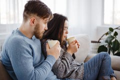 Unga par som hemma kopplar av med varma drinkar arkivfoto Unga par som hemma kopplar av med varma drinkar arkivfoto