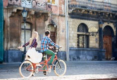 Unga turist- par, stilig man och tandem cykel f?r n?tt blond kvinnaridning l?ngs stadsgatan arkivfoto Unga turist- par, stilig man och tandem cykel f?r n?tt blond kvinnaridning l?ngs stadsgatan arkivfoto