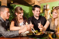 Ungdomarsom äter i thailändsk restaurang royaltyfria foton Ungdomarsom äter i thailändsk restaurang royaltyfria foton