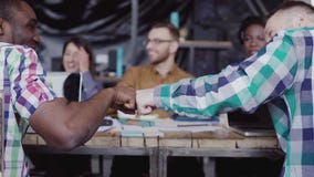 Ungt affärslag som tillsammans arbetar nära tabellen, idékläckning Två mans näven som hälsar sig stock video Ungt affärslag som tillsammans arbetar nära tabellen, idékläckning Två mans näven som hälsar sig stock video