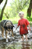 Ungt barn och hund som spelar i Muddy River royaltyfria foton Ungt barn och hund som spelar i Muddy River royaltyfria foton