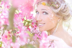 Ungt härligt elegant attraktivt flickaanseende i en skog nära blomningträd med långt hår som är blont i solig dag och makeup royaltyfria foton Ungt härligt elegant attraktivt flickaanseende i en skog nära blomningträd med långt hår som är blont i solig dag och makeup royaltyfria foton
