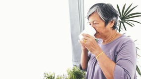 Unhappy lonely Asian senior woman with a cup of coffee alone at home, slow motion stock footage Unhappy lonely Asian senior woman with a cup of coffee alone at home, slow motion stock footage