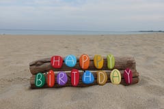 Happy Birthday message with a creative composition of colored stone letters on the beach