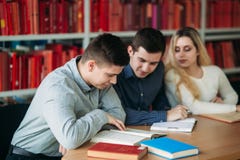 University students sitting together at the table with books and laptop. Happy young people doing group study in library stock photography University students sitting together at the table with books and laptop. Happy young people doing group study in library stock photography