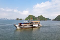 Uno de los muchos barcos del viaje que navegan entre las formaciones del karst en la bahía de Halong, Vietnam, en el Gulf of Tonk imagen de archivo Uno de los muchos barcos del viaje que navegan entre las formaciones del karst en la bahía de Halong, Vietnam, en el Gulf of Tonk imagen de archivo