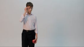 Uno studente vestito in una camicia bianca e nei pantaloni neri sta tenendo una mela in una mano, mentre l'altro raddrizza i suoi fotografia stock Uno studente vestito in una camicia bianca e nei pantaloni neri sta tenendo una mela in una mano, mentre l'altro raddrizza i suoi fotografia stock