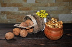 Unpeeled и, который слези грецкие орехи в баке в форме корзины и в глиняном горшке на деревянном столе стоковое изображение rf Unpeeled и, который слези грецкие орехи в баке в форме корзины и в глиняном горшке на деревянном столе стоковое изображение rf