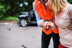 An unrecognizable man helping a young woman to walk after a car accident. Stock Image An unrecognizable man helping a young woman to walk after a car accident. Stock Image