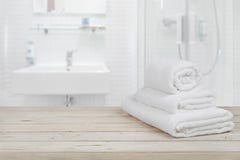 Unscharfer Badezimmerinnenhintergrund und weiße Badekurorttücher auf Holz Unscharfer Badezimmerinnenhintergrund und weiße Badekurorttücher auf Holz