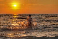 Uomini che giocano acqua alla spiaggia con il tramonto fotografie stock libere da diritti Uomini che giocano acqua alla spiaggia con il tramonto fotografie stock libere da diritti