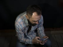 Uomo alla moda con una barba ed i baffi che occupa gli sguardi allo schermo del telefono cellulare immagini stock Uomo alla moda con una barba ed i baffi che occupa gli sguardi allo schermo del telefono cellulare immagini stock