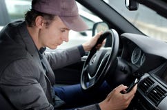 Uomo alla ruota facendo uso del telefono cellulare delle cellule mentre conducendo automobile immagini stock libere da diritti Uomo alla ruota facendo uso del telefono cellulare delle cellule mentre conducendo automobile immagini stock libere da diritti