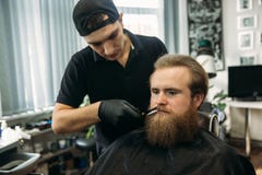 Uomo barbuto con la barba lunga che ottiene capelli alla moda che si radono, taglio di capelli, con il rasoio dal barbiere in par immagini stock libere da diritti Uomo barbuto con la barba lunga che ottiene capelli alla moda che si radono, taglio di capelli, con il rasoio dal barbiere in par immagini stock libere da diritti