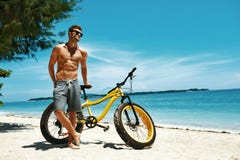 Uomo bello con il Sun della bici che si abbronza sulla spiaggia Vacanza di estate Immagini Stock Libere da Diritti Uomo bello con il Sun della bici che si abbronza sulla spiaggia Vacanza di estate Immagini Stock Libere da Diritti