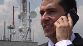 Uomo che parla sul telefono vicino alla torre cellulare Uomo che parla sul telefono vicino alla torre cellulare