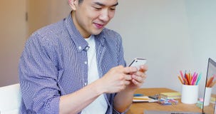Uomo che per mezzo del telefono cellulare al suo scrittorio archivi video Uomo che per mezzo del telefono cellulare al suo scrittorio archivi video