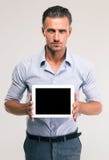 Uomo d'affari che mostra lo schermo di computer in bianco della compressa fotografie stock libere da diritti Uomo d'affari che mostra lo schermo di computer in bianco della compressa fotografie stock libere da diritti