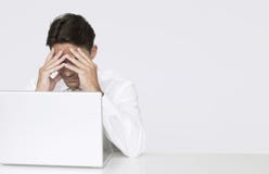 Uomo d'affari depresso Sitting With Laptop allo scrittorio in ufficio fotografia stock Uomo d'affari depresso Sitting With Laptop allo scrittorio in ufficio fotografia stock