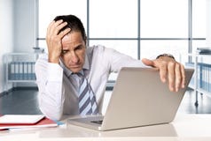 Uomo d'affari senior disperato nella crisi che lavora al computer portatile del computer alla scrivania nello sforzo sotto pressi immagini stock Uomo d'affari senior disperato nella crisi che lavora al computer portatile del computer alla scrivania nello sforzo sotto pressi immagini stock
