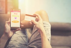 Uomo di compera online facendo uso di acquisto dello smartphone nel mercato del sito Web online e mani che tengono la carta di cr immagine stock Uomo di compera online facendo uso di acquisto dello smartphone nel mercato del sito Web online e mani che tengono la carta di cr immagine stock