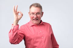 Uomo europeo senior nel segno GIUSTO di rappresentazione rossa della camicia fotografie stock Uomo europeo senior nel segno GIUSTO di rappresentazione rossa della camicia fotografie stock