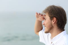 Uomo felice che esplora sulla spiaggia con la mano sulla fronte fotografie stock Uomo felice che esplora sulla spiaggia con la mano sulla fronte fotografie stock