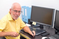 Uomo maturo che lavora con la tavola dei grafici nel suo ufficio fotografie stock Uomo maturo che lavora con la tavola dei grafici nel suo ufficio fotografie stock