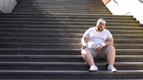 Uomo obeso in abiti sportivi che si siedono sulle scale, mancanza di motivazione per perdita di peso immagini stock libere da diritti Uomo obeso in abiti sportivi che si siedono sulle scale, mancanza di motivazione per perdita di peso immagini stock libere da diritti