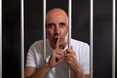 Uomo in prigione che gesturing per tenere silenzio fotografia stock Uomo in prigione che gesturing per tenere silenzio fotografia stock