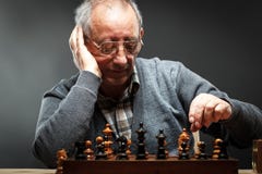 Uomo senior che pensa alla sua prossima tappa in un gioco di scacchi Immagini Stock Libere da Diritti Uomo senior che pensa alla sua prossima tappa in un gioco di scacchi Immagini Stock Libere da Diritti