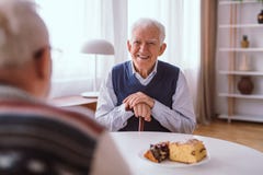 Uomo senior felice che ride con il suo vecchio amico sopra il pezzo di dolce fotografia stock libera da diritti Uomo senior felice che ride con il suo vecchio amico sopra il pezzo di dolce fotografia stock libera da diritti