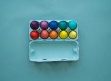 Uova di Pasqua variopinte tinte mano vibrante in una scatola delle uova del cartone osservata fotografia stock Uova di Pasqua variopinte tinte mano vibrante in una scatola delle uova del cartone osservata fotografia stock