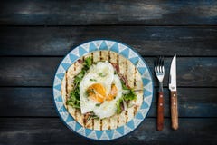 Uova fritte sulla tortiglia della farina con insalata verde e formaggio Idea utile del pranzo o della prima colazione Coltello de immagini stock libere da diritti Uova fritte sulla tortiglia della farina con insalata verde e formaggio Idea utile del pranzo o della prima colazione Coltello de immagini stock libere da diritti
