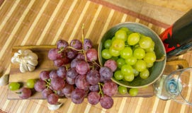 Upper view of a red and yellow muscat colored grape, bottle of wine, garlic and a glass on a wooden board - still life Stock Photography Upper view of a red and yellow muscat colored grape, bottle of wine, garlic and a glass on a wooden board - still life Stock Photography