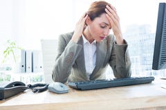 Upset business woman with head in hands in front of computer at office stock image Upset business woman with head in hands in front of computer at office stock image