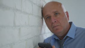 Upset Businessman Thinking Disappointed with Cell Phone in Hand stock photo Upset Businessman Thinking Disappointed with Cell Phone in Hand stock photo