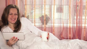 Urocza kobieta z filiżanką, pastylki komputerową patrzeje kamerą i ono uśmiecha się zbiory wideo Urocza kobieta z filiżanką, pastylki komputerową patrzeje kamerą i ono uśmiecha się zbiory wideo