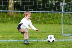 Urocza śliczna małe dziecko chłopiec bawić się piłkę nożną i futbol na polu zdjęcie stock Urocza śliczna małe dziecko chłopiec bawić się piłkę nożną i futbol na polu zdjęcie stock