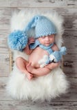 Uroczy sypialny dziecko w kapeluszu z dużym pompon na puszystym łóżku polowym zdjęcie royalty free Uroczy sypialny dziecko w kapeluszu z dużym pompon na puszystym łóżku polowym zdjęcie royalty free