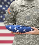 US Army soldier holding folded USA flag before his chest