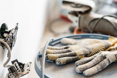 Work gloves in the foreground. Lots of tools and cans of paint in the background. Concept of repair in the house stock photo Work gloves in the foreground. Lots of tools and cans of paint in the background. Concept of repair in the house stock photo