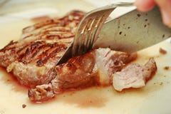 Utilice el cuchillo y la bifurcación al filete cortado del cerdo foto de archivo Utilice el cuchillo y la bifurcación al filete cortado del cerdo foto de archivo