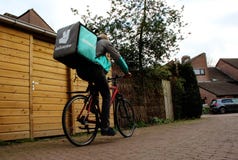 Utrecht, Нидерланд, 19-ое февраля 2019: Фрилансер Deliveroo на его велосипеде идя к следующей доставке стоковые изображения rf Utrecht, Нидерланд, 19-ое февраля 2019: Фрилансер Deliveroo на его велосипеде идя к следующей доставке стоковые изображения rf