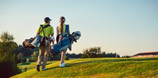 Utrustar bärande golf för lyckliga par, medan den bärande ställningen hänger löst royaltyfri bild Utrustar bärande golf för lyckliga par, medan den bärande ställningen hänger löst royaltyfri bild