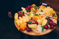 Uva servente del cameriere, assortimento arancio di frutti tropicali della pera della banana su un piatto bianco al ristorante pe immagini stock Uva servente del cameriere, assortimento arancio di frutti tropicali della pera della banana su un piatto bianco al ristorante pe immagini stock